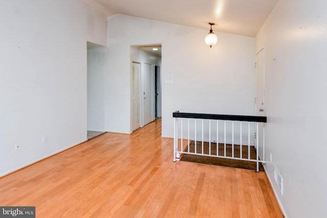 unfurnished room with hardwood / wood-style floors and vaulted ceiling