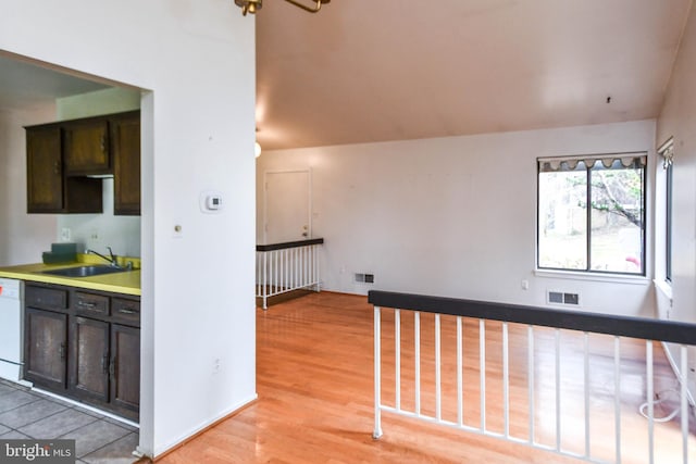 kitchen with dark brown cabinets, light hardwood / wood-style floors, dishwasher, and sink