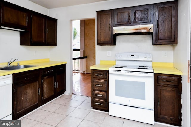 kitchen featuring light tile patterned flooring, dark brown cabinets, white appliances, and sink