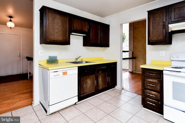 kitchen featuring dark brown cabinets, white appliances, sink, and light hardwood / wood-style flooring