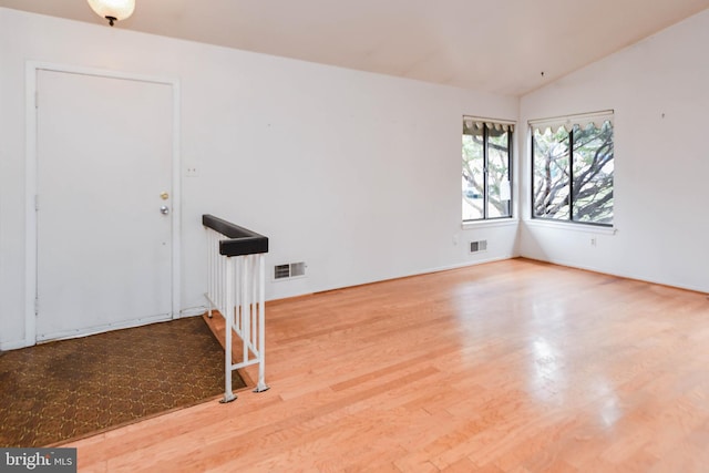 empty room with hardwood / wood-style floors and vaulted ceiling