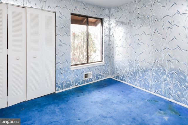 unfurnished bedroom featuring multiple windows, a closet, and dark carpet