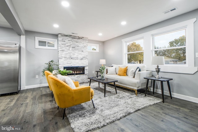 living room with a stone fireplace and dark hardwood / wood-style flooring