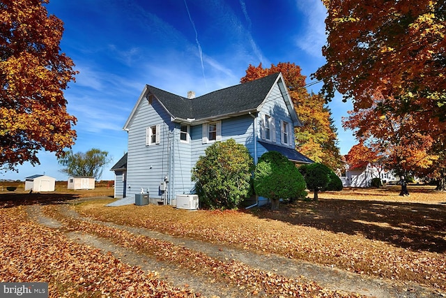 view of home's exterior with central AC and a storage shed