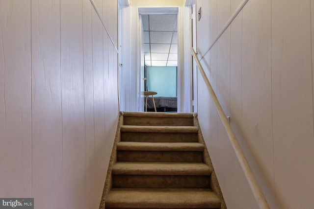 stairs featuring wood walls