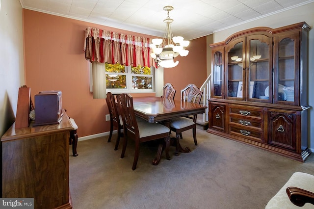 carpeted dining space with ornamental molding and a chandelier