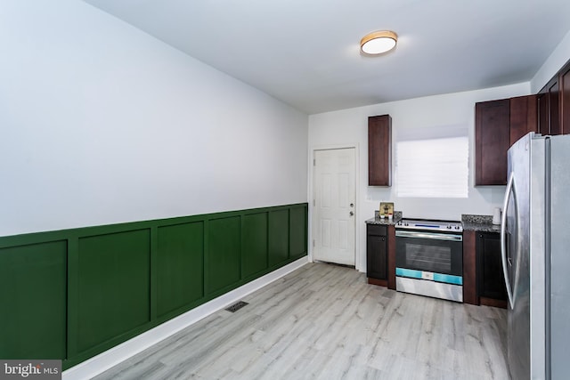 kitchen with stainless steel appliances, dark brown cabinetry, and light hardwood / wood-style flooring