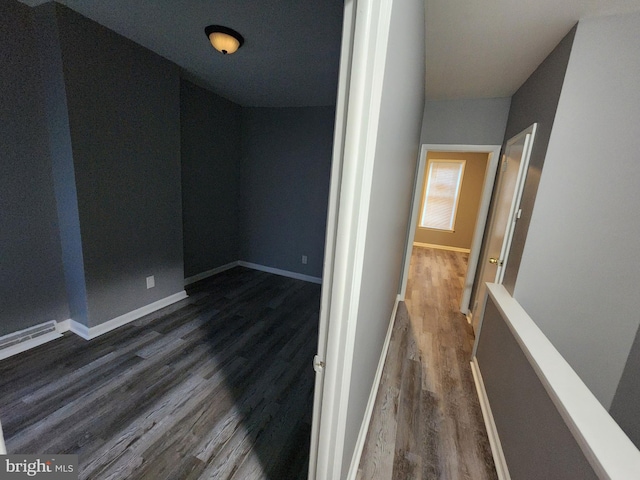 hallway featuring lofted ceiling and dark wood-type flooring