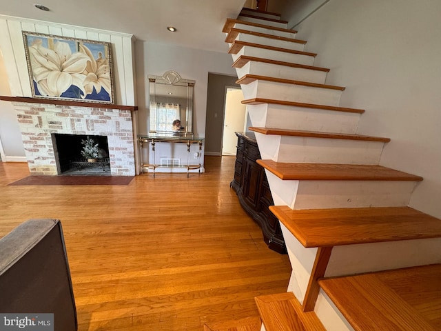 staircase with hardwood / wood-style flooring and a fireplace