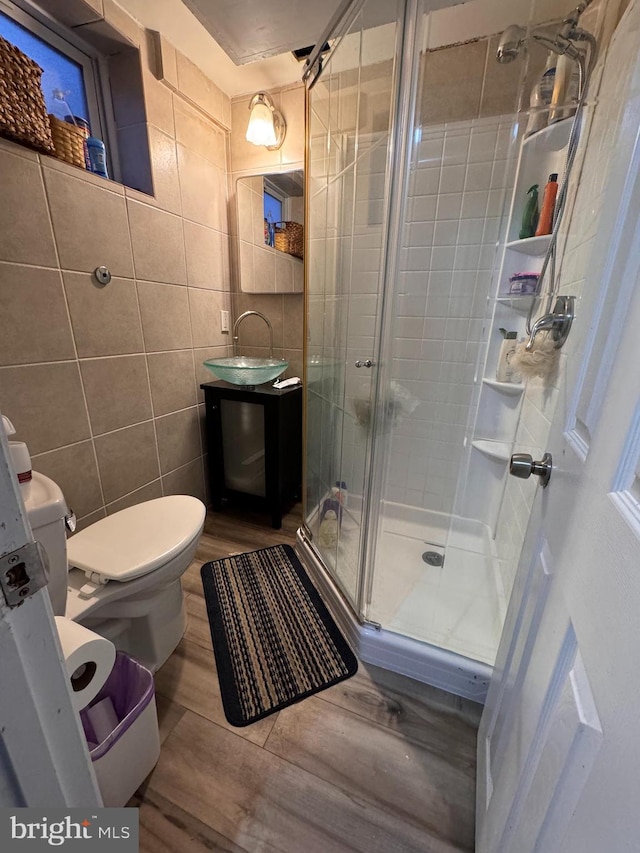 bathroom featuring vanity, hardwood / wood-style flooring, toilet, tile walls, and walk in shower