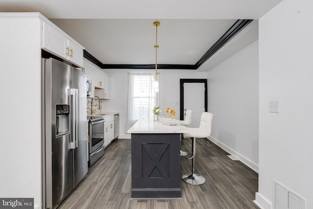 1107 S Carey St, Baltimore, MD 21223 - kitchen featuring appliances with stainless steel finishes, white cabinets, a breakfast bar, dark wood-style floors, and crown molding