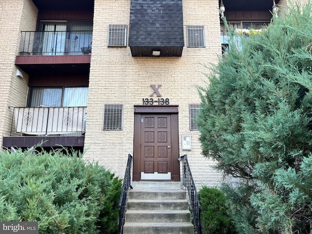 doorway to property featuring brick siding and a balcony