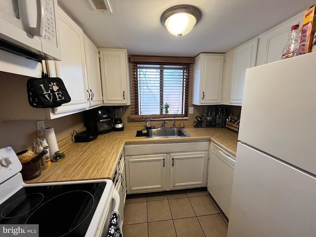 kitchen featuring white appliances, white cabinets, light tile patterned floors, and sink