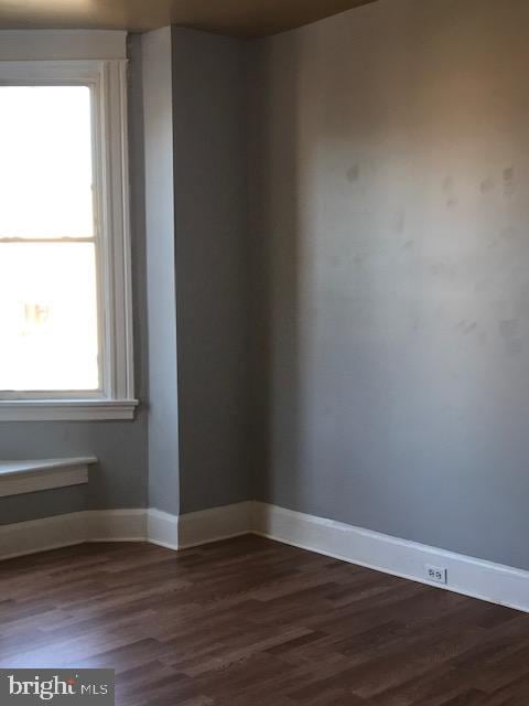 unfurnished room featuring dark wood-type flooring and plenty of natural light