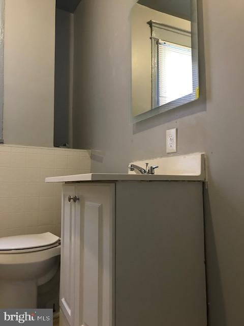 bathroom featuring vanity, toilet, and tile walls