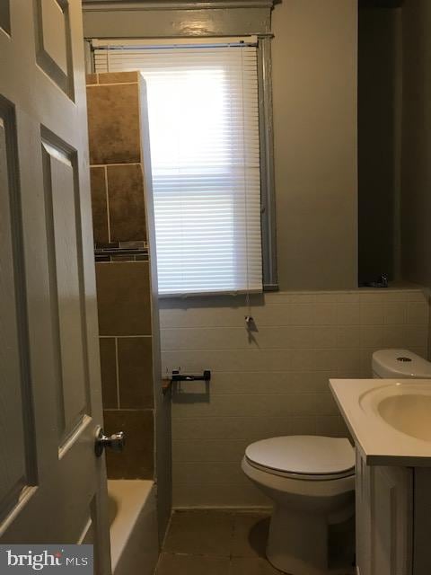 full bathroom with toilet, tile patterned flooring, separate shower and tub, vanity, and tile walls