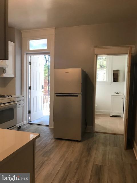 kitchen featuring a healthy amount of sunlight, white range, stainless steel fridge, white cabinets, and hardwood / wood-style flooring