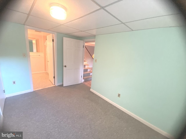 basement featuring a paneled ceiling and carpet floors