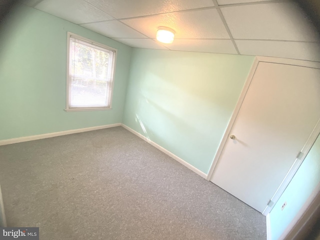 carpeted empty room featuring a drop ceiling