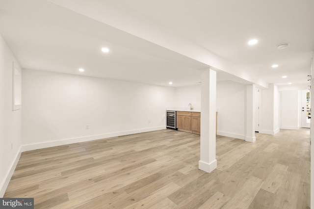 basement featuring light hardwood / wood-style flooring and beverage cooler