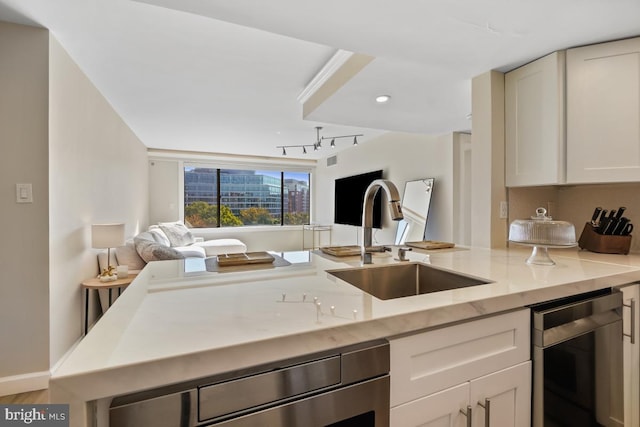 kitchen featuring white cabinets, sink, beverage cooler, and light stone counters