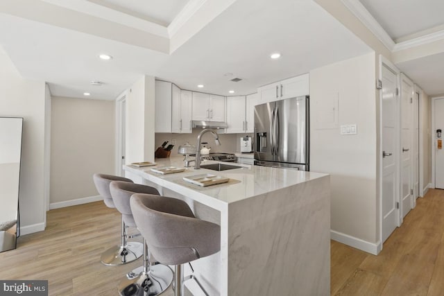 kitchen featuring stainless steel fridge, white cabinetry, kitchen peninsula, and light hardwood / wood-style floors