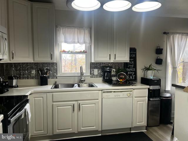 kitchen with dishwasher, white cabinetry, sink, and tasteful backsplash