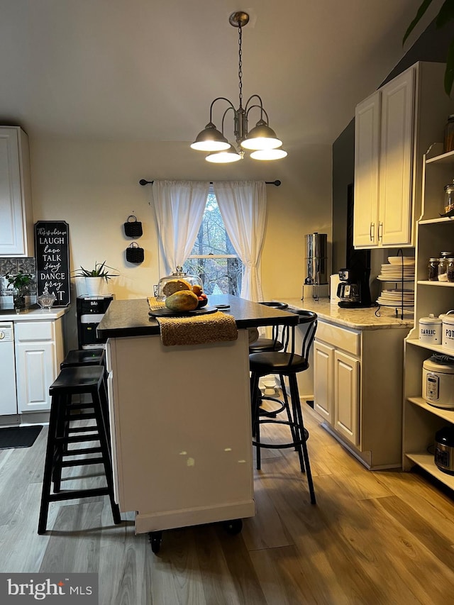 kitchen featuring white cabinets, a kitchen breakfast bar, hardwood / wood-style flooring, and white dishwasher