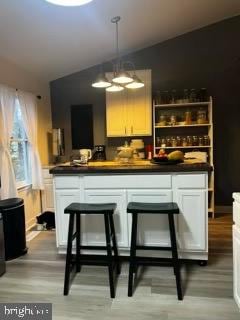 bar featuring white cabinets, hardwood / wood-style floors, and decorative light fixtures