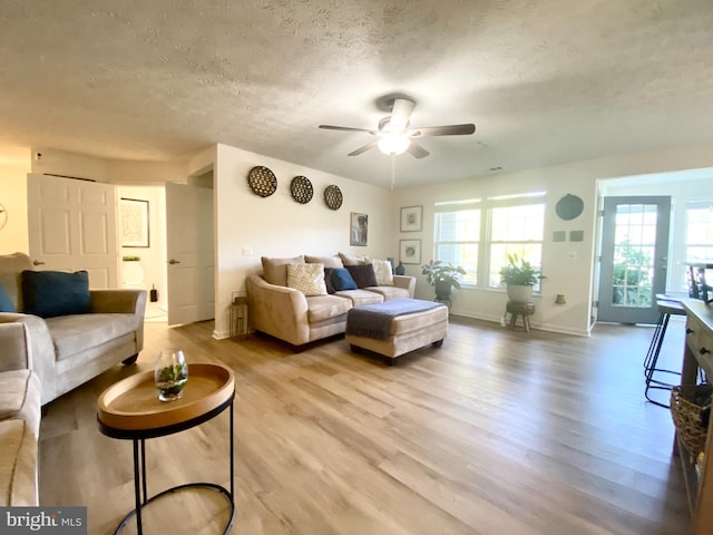 living room featuring a textured ceiling, ceiling fan, and light hardwood / wood-style flooring