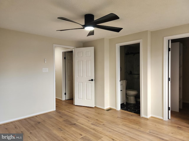 unfurnished bedroom with ensuite bath, ceiling fan, a textured ceiling, and light wood-type flooring