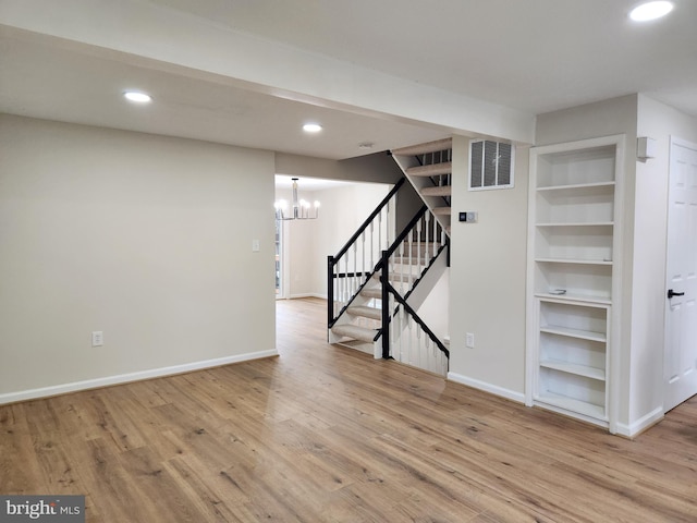 basement featuring hardwood / wood-style flooring and a notable chandelier