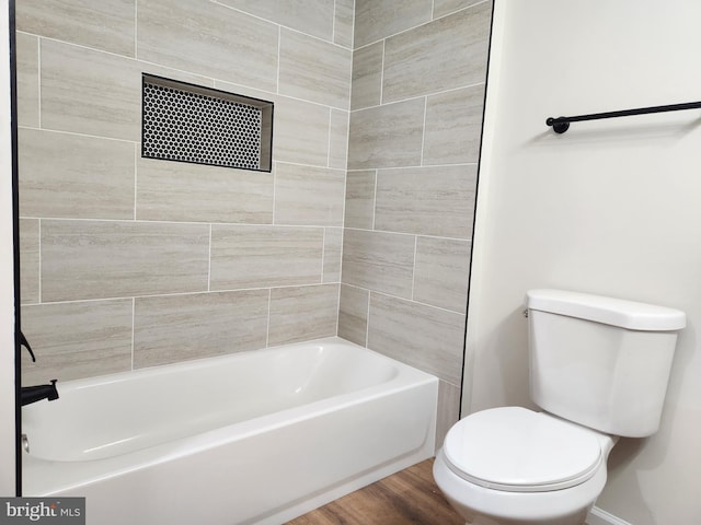 bathroom featuring tiled shower / bath, wood-type flooring, and toilet