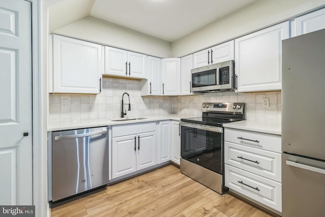 kitchen featuring decorative backsplash, appliances with stainless steel finishes, sink, light hardwood / wood-style floors, and white cabinetry