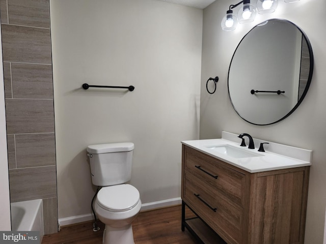 bathroom featuring a bath, vanity, hardwood / wood-style flooring, and toilet