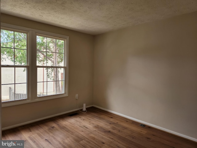 spare room with wood-type flooring and a textured ceiling