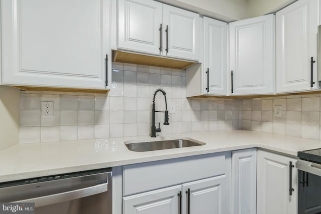 kitchen featuring backsplash, white cabinetry, sink, and appliances with stainless steel finishes