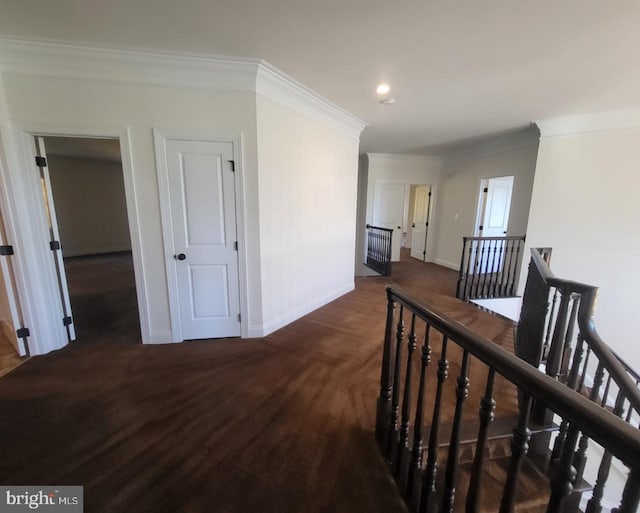 hallway featuring ornamental molding and dark colored carpet