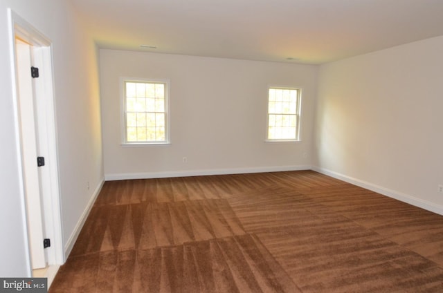 empty room with a healthy amount of sunlight and dark carpet