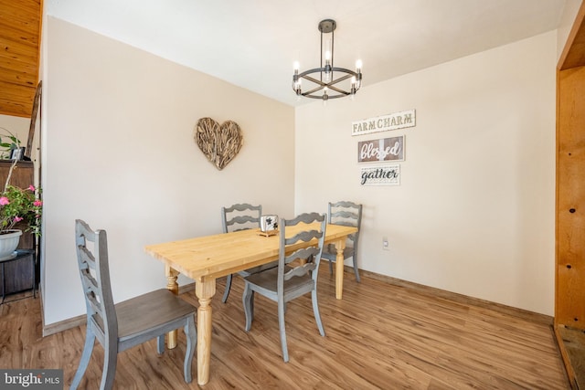 dining area with light hardwood / wood-style floors and a notable chandelier