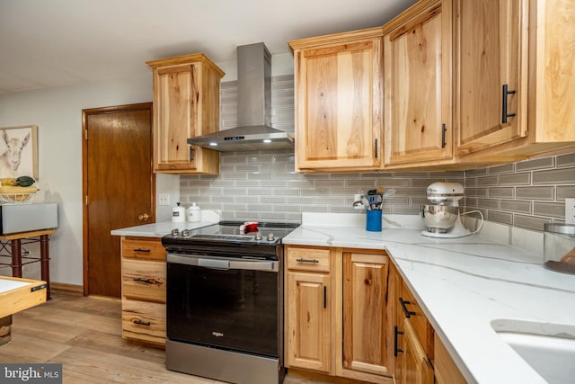 kitchen with wall chimney range hood, backsplash, electric range, light wood-type flooring, and light stone counters