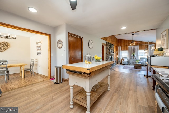 kitchen featuring lofted ceiling, wooden walls, light hardwood / wood-style flooring, hanging light fixtures, and a chandelier