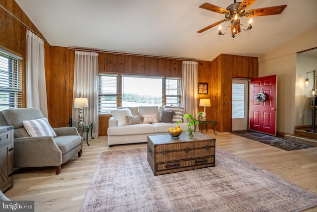 living room featuring ceiling fan, a healthy amount of sunlight, light hardwood / wood-style flooring, and wood walls