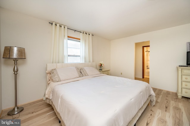 bedroom with ensuite bathroom and light wood-type flooring