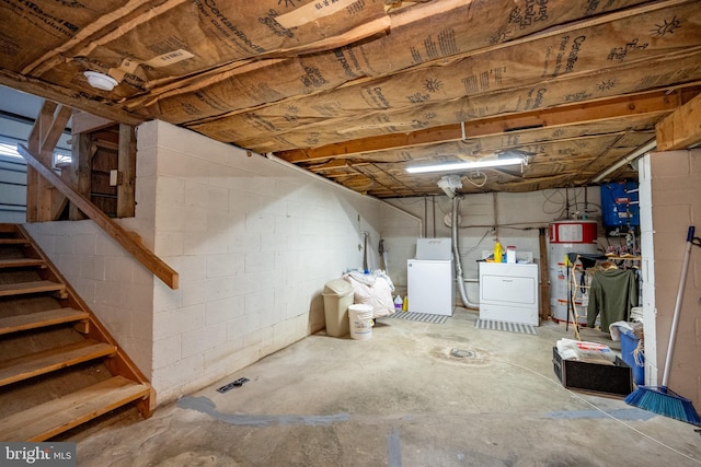 basement featuring washing machine and clothes dryer, white refrigerator, and gas water heater