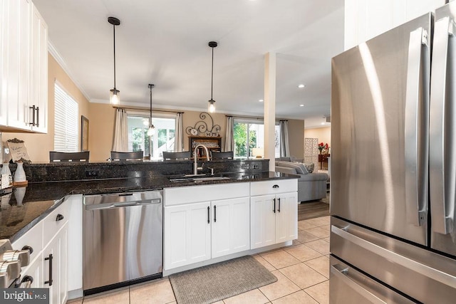 kitchen featuring sink, stainless steel appliances, dark stone counters, pendant lighting, and white cabinets