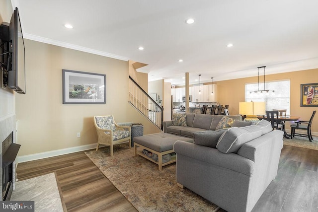 living room with crown molding, a chandelier, and dark hardwood / wood-style floors