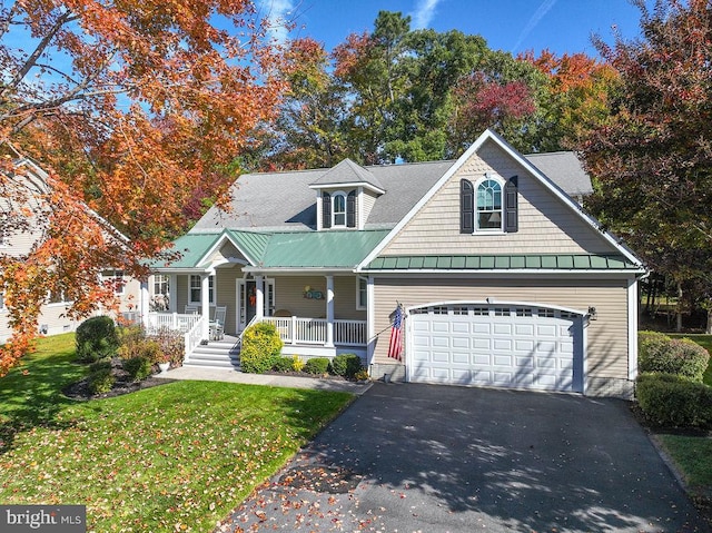 view of front of home with covered porch, a front yard, and a garage