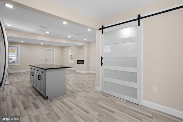 kitchen with gray cabinets, a barn door, light wood-type flooring, and a kitchen island