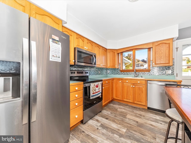 kitchen featuring light hardwood / wood-style floors, tasteful backsplash, stainless steel appliances, and sink